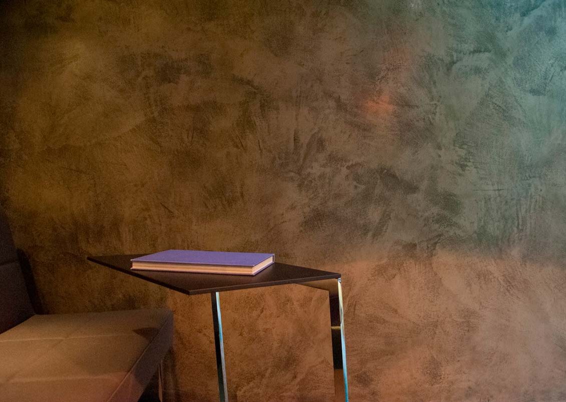 Close up of Armourcoat Polished Plaster Leatherstone wall finish in Brunner showroom with table and chair in foreground