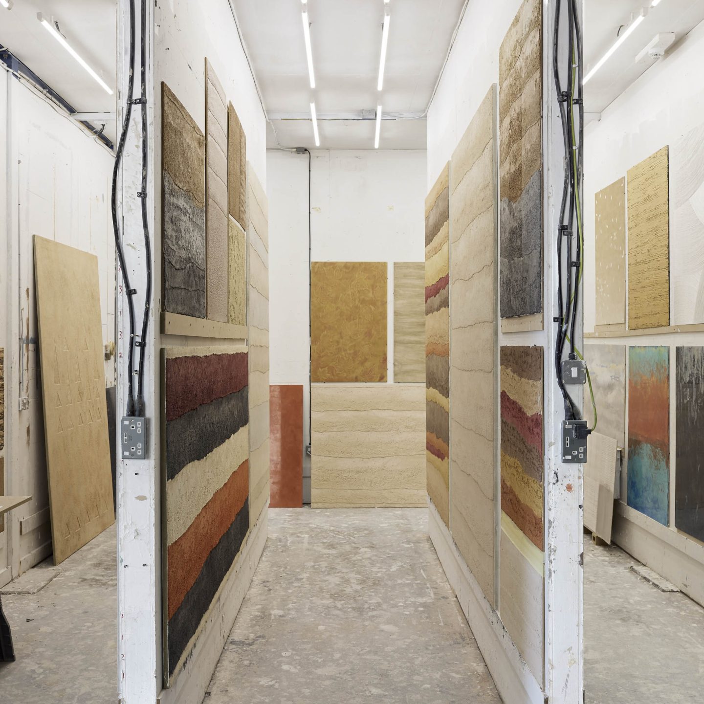 Armourcoat workshop displaying large decorative plaster and surface samples in a range of colors, textures and finishes.