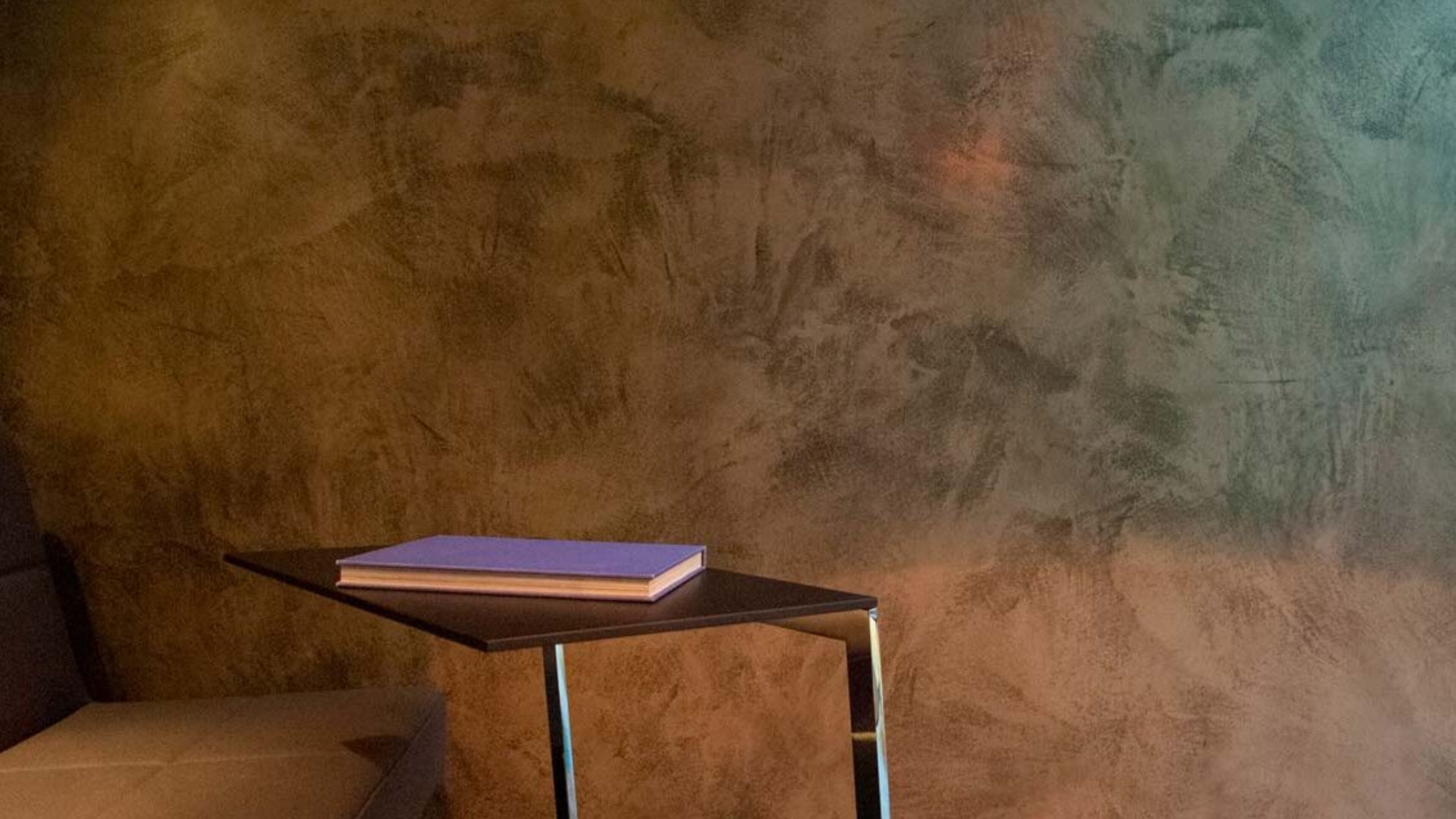 Close up of Armourcoat Polished Plaster Leatherstone wall finish in Brunner showroom with table and chair in foreground