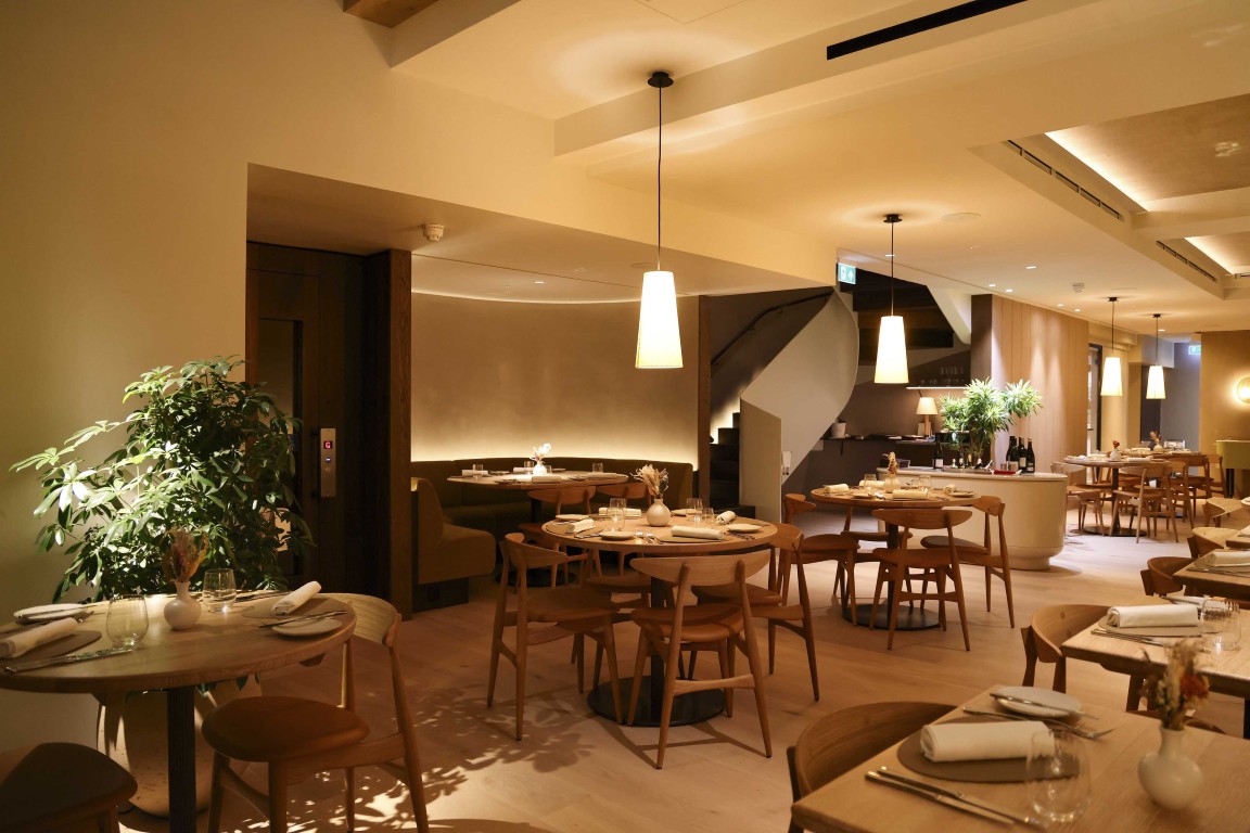 Main dining area at 74 Charlotte Street, designed by Chris Bagot Architects, with curved architectural details, neutral plaster walls and timber furnishings.