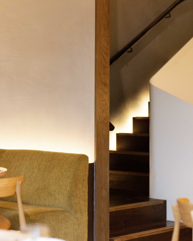 Curved staircase at 74 Charlotte Street restaurant, featuring Armourcoat Smooth Polished Plaster alongside timber detailing and upholstered seating.
